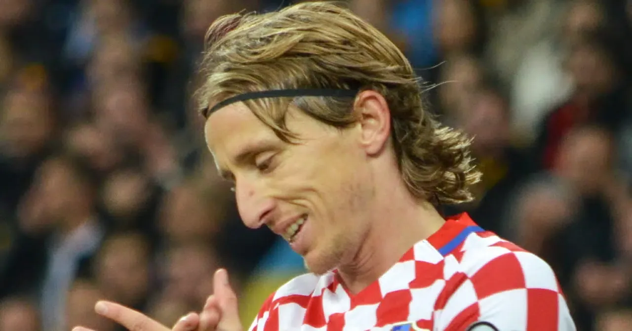 Footballer Luka Modric looking downwards and applauding while playing in the red and white home shirt of the Croatia national football team inside a stadium