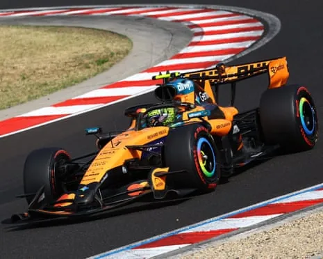 Lando Norris' orange MLaren Formula One car navigates a corner on a race track with red and white striped kerbs