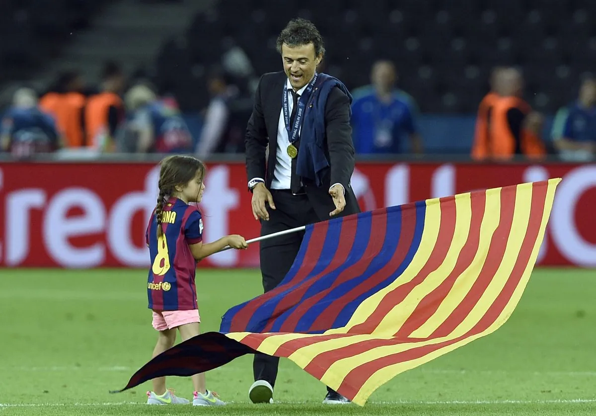 Barcelona's coach Luis Enrique and his daughter Xana wave a flag after the UEFA Champions League Final football match between Juventus and FC Barcelona at the Olympic Stadium in Berlin on June 6, 2015.
